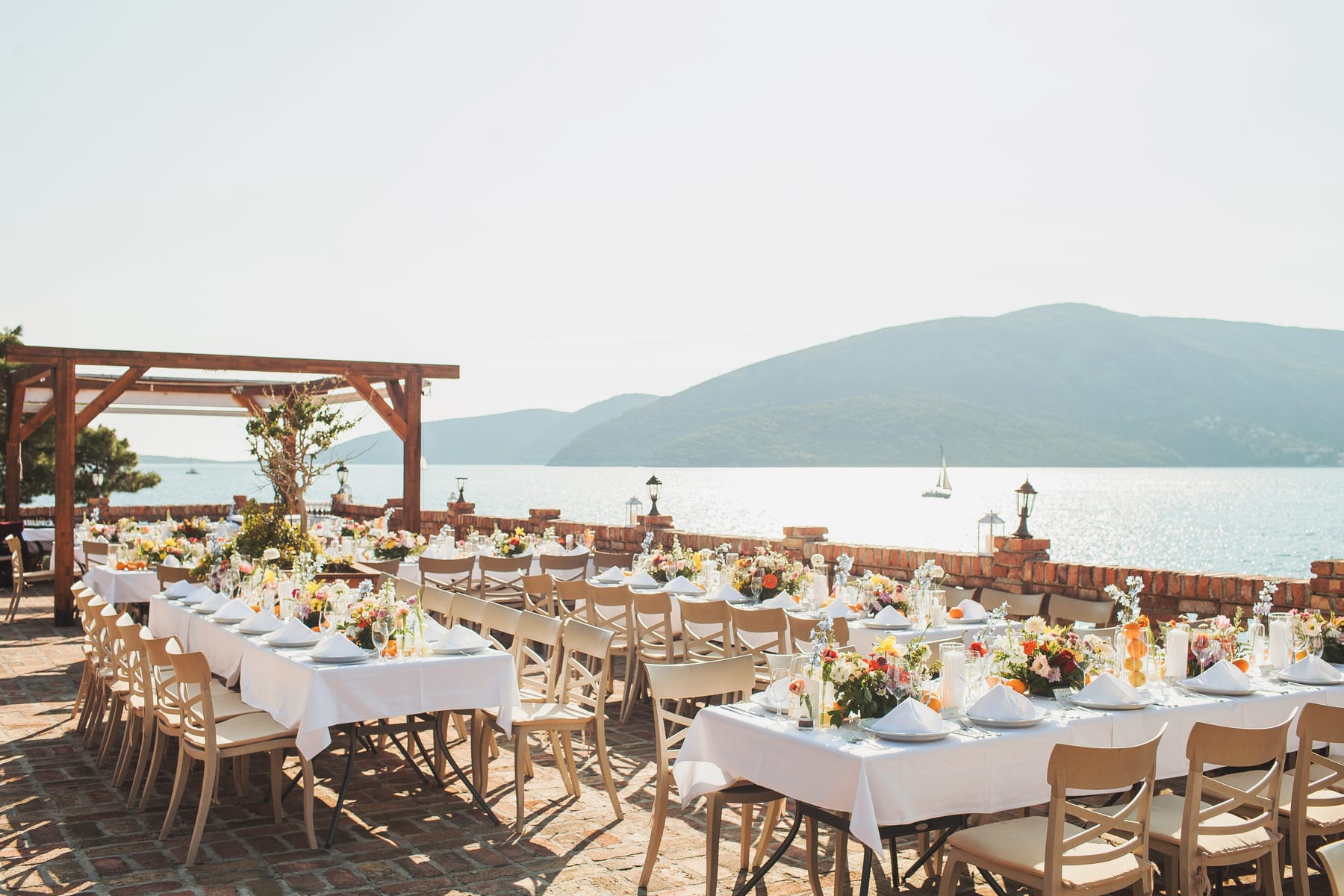 Sunlit long-table brunch with coral florals over the Adriatic